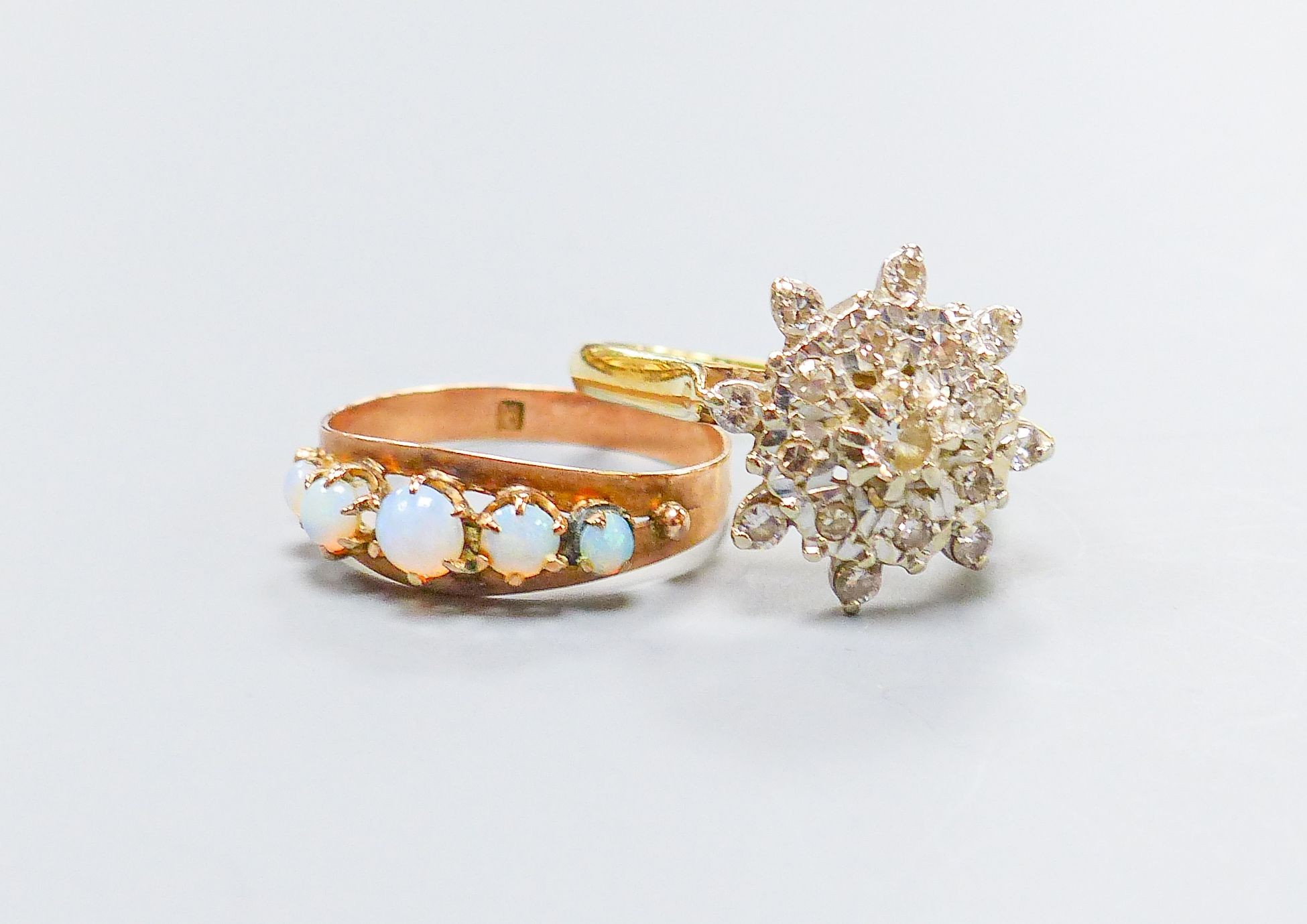 A yellow metal (stamped 9) and graduated five stone white opal set half hoop ring, size M, gross 1.2 grams and and 18ct gold and diamond chip cluster ring, gross 4.6 grams.